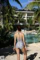 A woman in a bathing suit standing on a beach next to a pool.