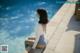 A woman sitting on the edge of a swimming pool.