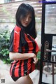 A woman in a red and black striped shirt is posing for a picture.