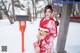 A woman in a red kimono standing in the snow.