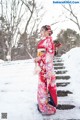 A woman in a red kimono standing in the snow.