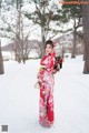 A woman in a red kimono standing in the snow.