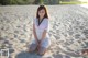 A woman sitting on a sandy beach next to the ocean.