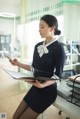 A woman in a business suit sitting at a desk with a tablet.