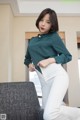 A woman in a green shirt and white pants posing for a picture.