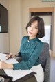 A woman sitting at a desk writing on a piece of paper.