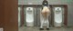 A woman in a school uniform is standing in front of urinals.