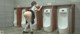 A woman standing in front of a row of urinals.