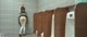 A woman standing in front of urinals in a public restroom.