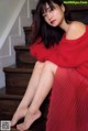 A woman in a red dress sitting on the stairs.