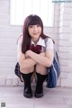 A young woman in a school uniform sitting on the floor.