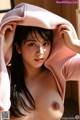 A naked asian woman in a pink sweater is posing for the camera.