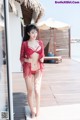 A woman in a red lingerie standing on a wooden deck.