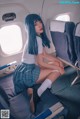 A woman with blue hair sitting on an airplane seat.