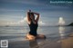 A woman in a black bathing suit sitting in the water.