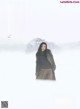 A woman standing in the snow wearing a coat.